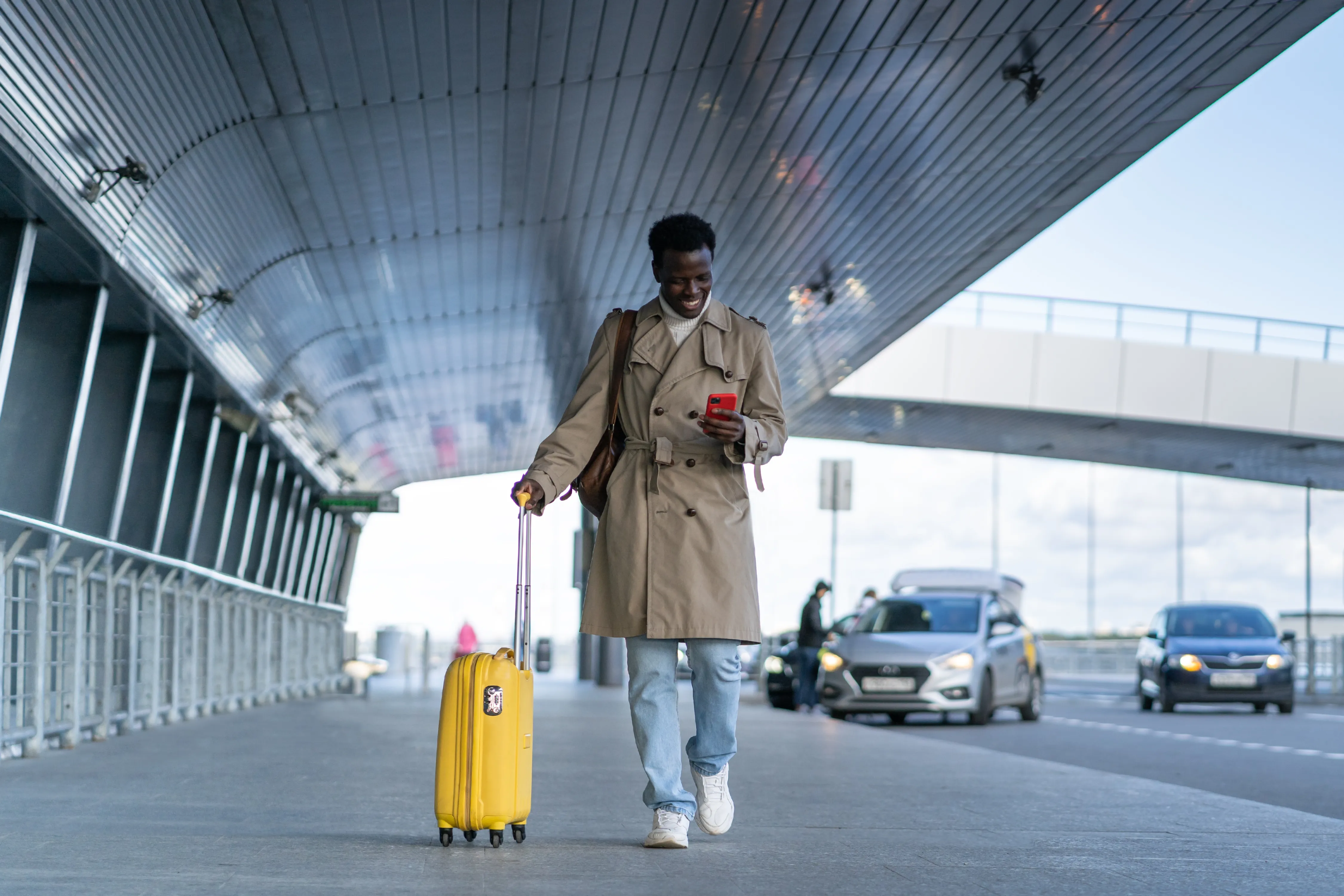 man walking with a suitcase outside an airport