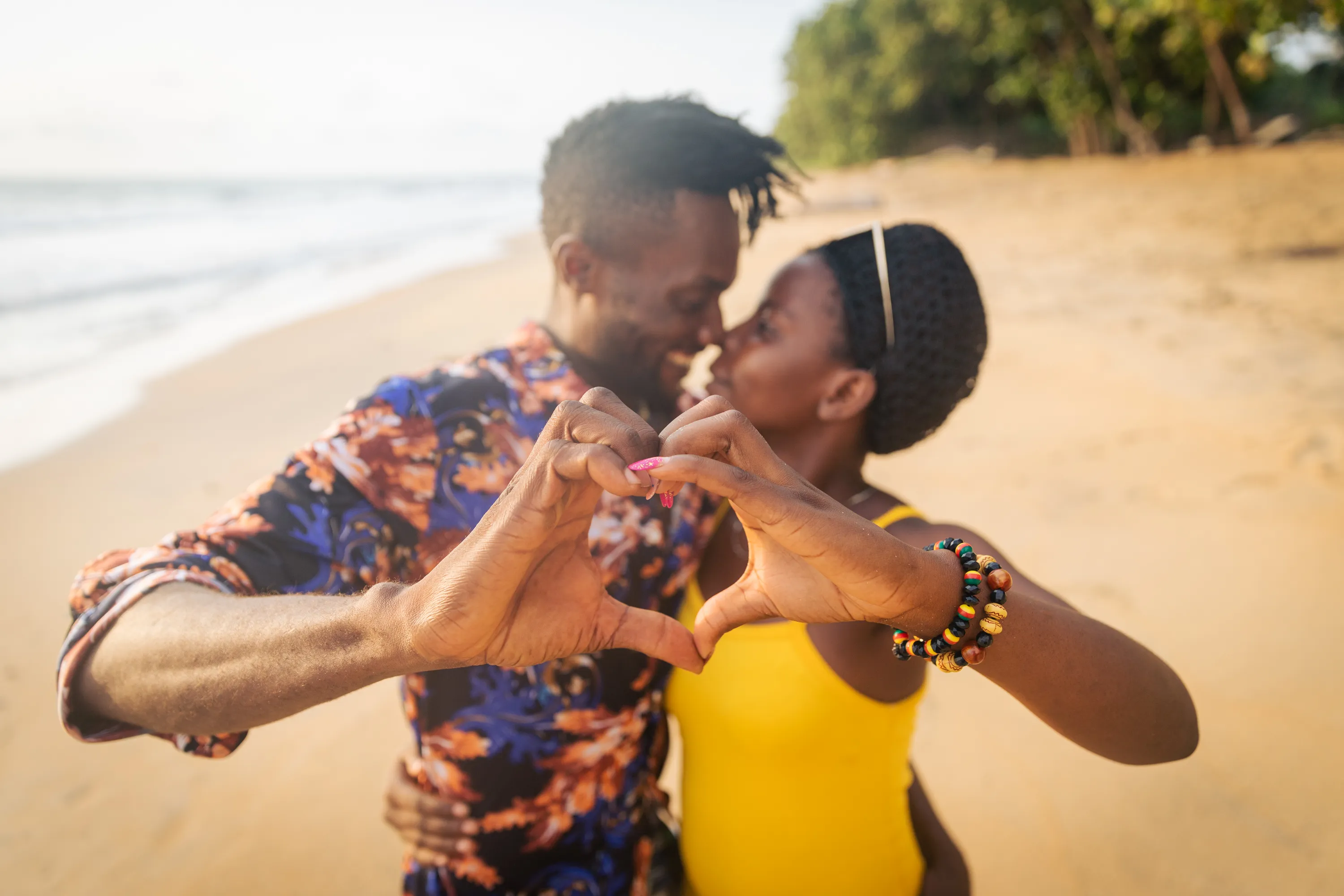 A couple on the beach making hearts with their hands